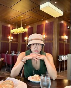 a woman wearing a hat sitting at a table with food and drinks in front of her