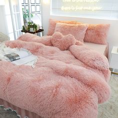 a bed with pink fluffy blankets and pillows