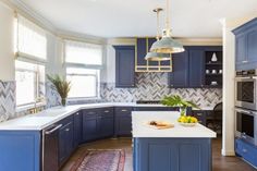 a large kitchen with blue cabinets and white counter tops, an island in the middle