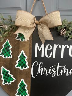 a merry christmas sign hanging on the front door with pine cones and evergreens around it