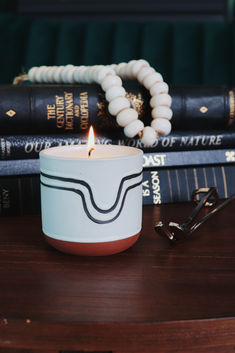 a candle sitting on top of a wooden table next to some books and eyeglasses