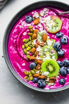 a bowl of smoothie with kiwi, blueberries and almonds on top