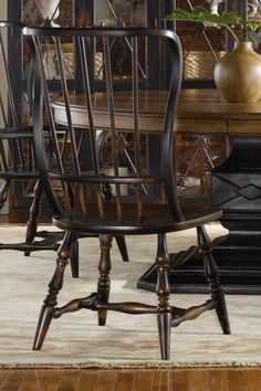 a dining room table with chairs and a vase on top of the table in front of it