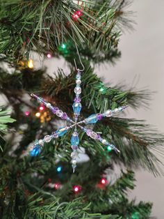 a snowflake ornament is hanging from a christmas tree with lights on it