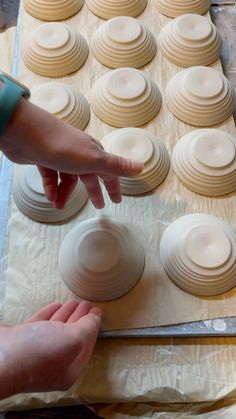 a person reaching for something in the middle of a doughnut pan on top of wax paper