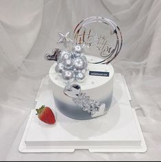 a white cake with silver decorations and a strawberry