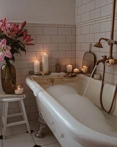 a bathtub with candles and flowers in it