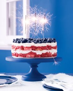 a red, white and blue cake with sparklers on top is sitting on a table