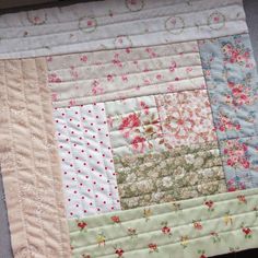 a close up of a patchwork quilt on a table cloth with flowers and dots