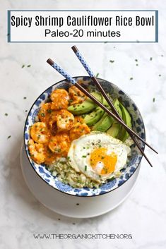 a bowl filled with rice and shrimp next to chopsticks on top of it