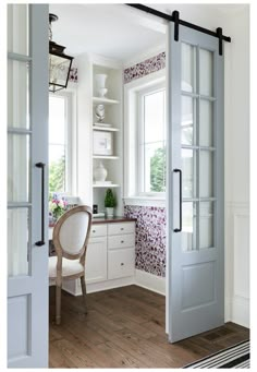 an open door leading to a kitchen with white walls and wood flooring in the center