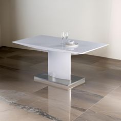 a white table with two wine glasses on it sitting in front of a beige wall