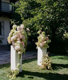 two tall vases with flowers are in the grass