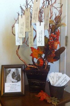 an arrangement of autumn leaves and other items on a table with cards attached to the branches