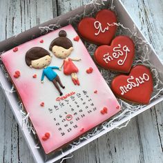 two decorated heart shaped cookies in a box with the date on it and calendar for march