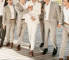 a group of men standing next to each other on a wooden floor in suits and ties