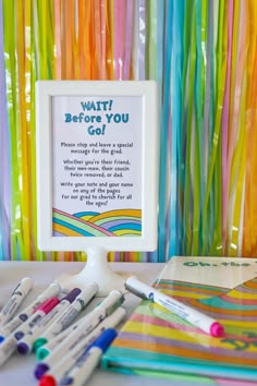 there are many pens and markers on the table next to this sign that says wait before you go