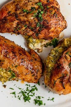 three pieces of chicken on a white plate with parsley sprinkled around it