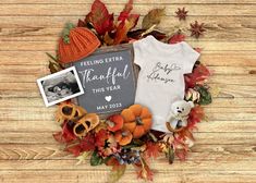 a baby's first thanksgiving outfit and other items are arranged in a wreath on a wooden surface