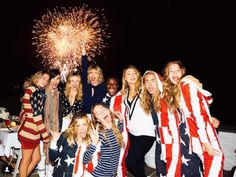 a group of women standing next to each other in front of a firework display