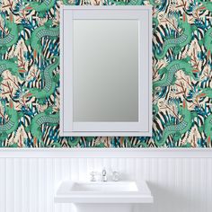 a bathroom sink sitting under a mirror next to a wall mounted faucet in front of a green and pink patterned wall