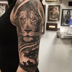 a woman with a lion tattoo on her arm in front of some pictures and paintings