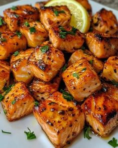 some chicken on a white plate with lemon wedges and garnished parsley