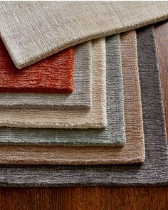 a pile of different colored rugs sitting on top of a wooden floor