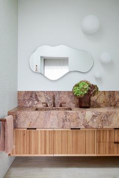 a bathroom with marble counter tops and wooden cabinets, along with a plant in the corner