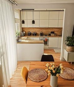 a kitchen and dining room with wooden floors, white cabinets and counter tops is seen in this image