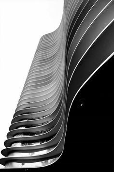 a black and white photo of the side of a building with curved metal lines on it