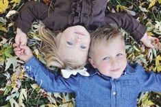 two young children laying on top of leaves