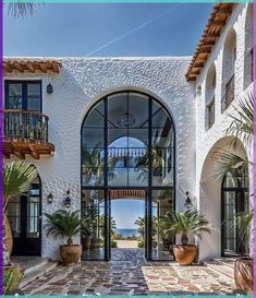 an entrance to a white stucco building with large windows and plants on the outside wall