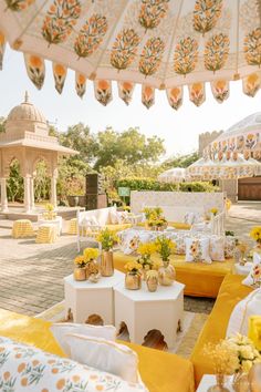 an outdoor seating area with tables and umbrellas in the background, surrounded by yellow flowers