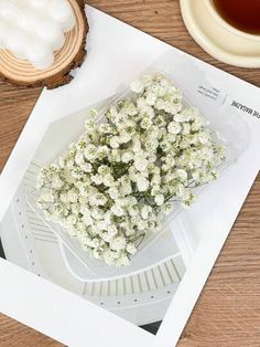 a bunch of white flowers sitting on top of a table next to a cup of tea