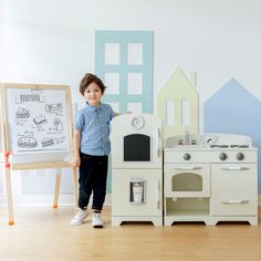 a little boy standing in front of a play kitchen