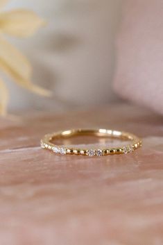 a yellow gold band with small diamonds on it, sitting on top of a bed