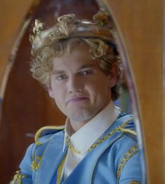 a young man wearing a blue and gold outfit looking at his reflection in a mirror