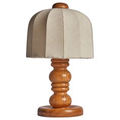 a wooden table lamp with a white shade on the base and a beige fabric lampshade