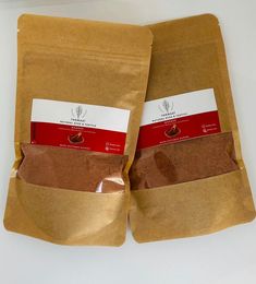 two bags of ground coffee sitting on top of a white counter next to each other