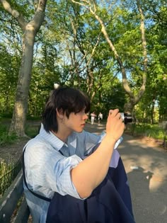 a woman sitting on a park bench taking a photo