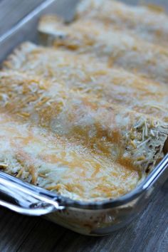 a casserole dish with cheese in it on top of a wooden table next to a fork