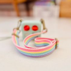 the camera strap is attached to an apple watch with a rainbow colored pattern on it