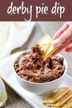 a hand dipping some food into a bowl with crackers on the side and text overlay