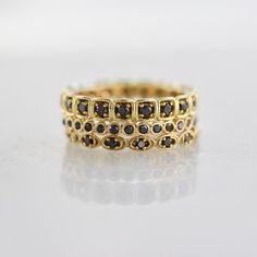 a gold ring with black diamonds on it's sides, sitting on a white surface