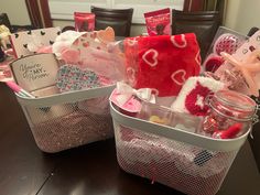 two baskets filled with valentine's day items on a table in front of a mirror