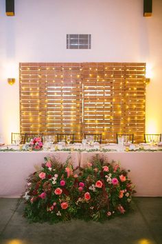 the table is set with flowers and place settings for an elegant dinner or reception in front of a wooden slatted wall