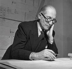 an old black and white photo of a man sitting at a desk with papers on it