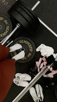 a woman is sitting on the floor in front of a barbell and weight plates