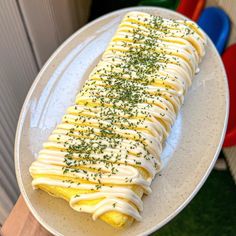 a white plate topped with an omelet covered in cream and chives on top of a wooden table